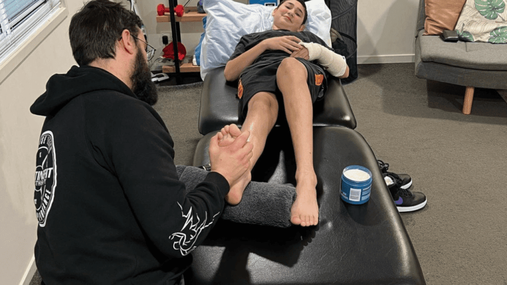 Male patient receiving physical therapy on his ankle in a physio treatment room.