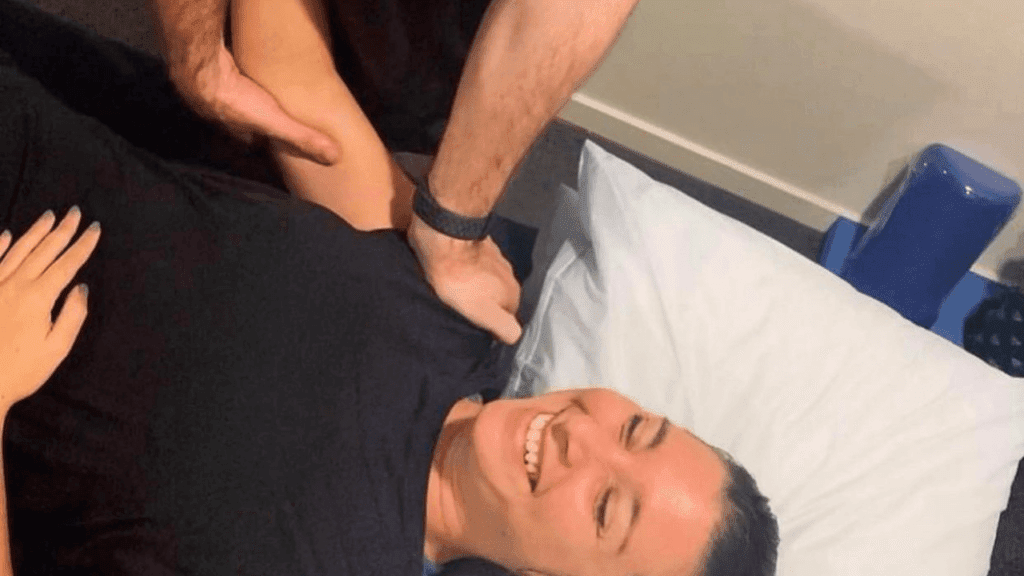 A smiling patient receiving physiotherapy treatment for shoulder pain from a professional physiotherapist.