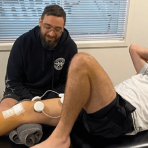 Patient undergoing physiotherapy for knee injury in a treatment room.